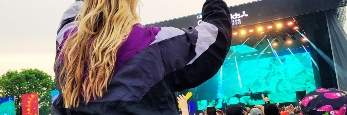 Model at Cream Fields music festival wearing Vintage Recovery 90s windbreaker dancing on shoulders